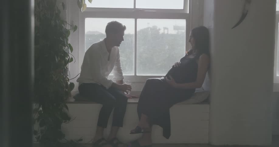 A man and woman talk and he touches her pregnant belly