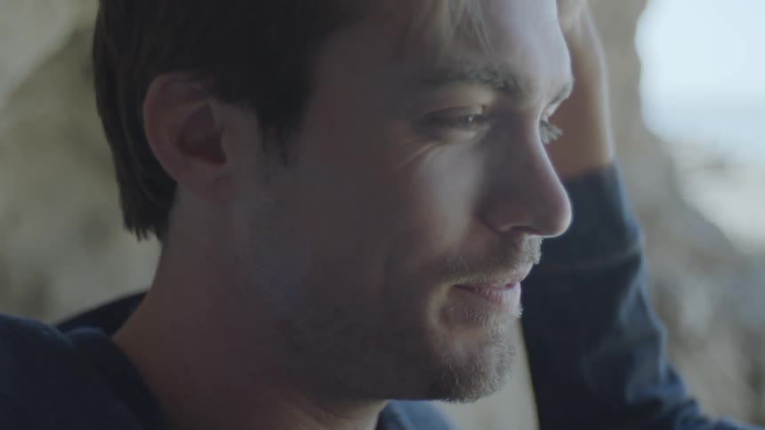 A young woman smoothing back the hair of a man while he smiles at her