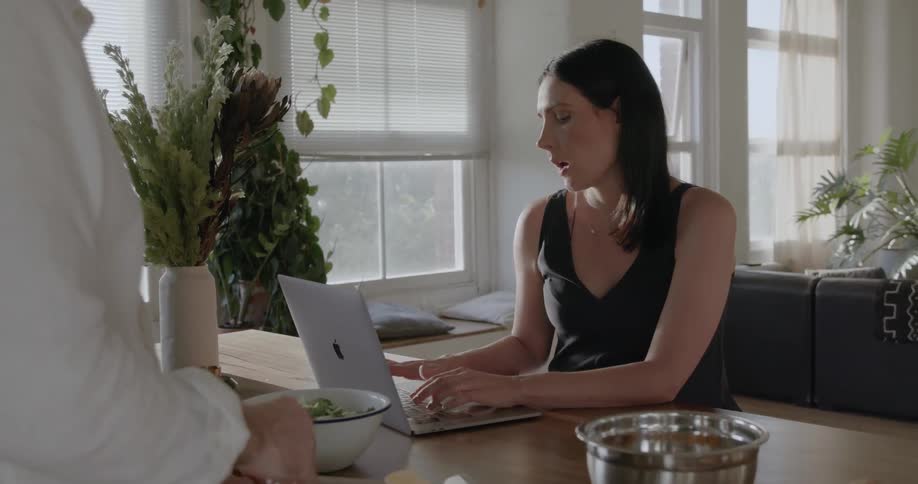 A man talks to a woman using a laptop