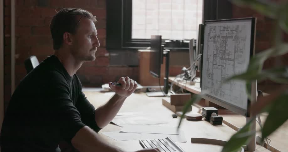 A man sits at an office desk using a computer