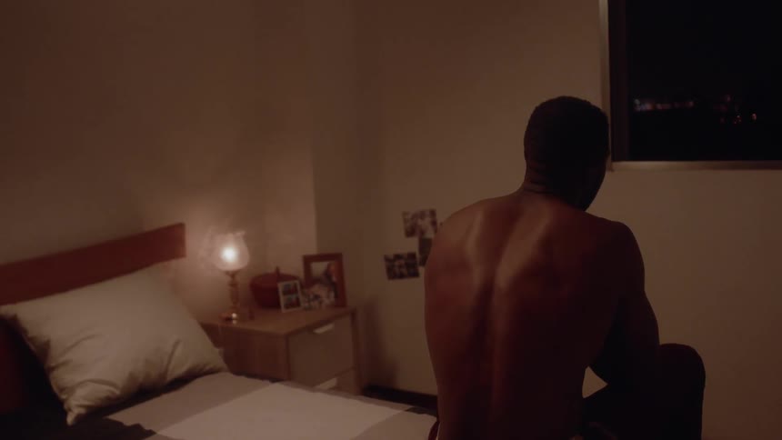 Man sits at the edge of a bed looking up