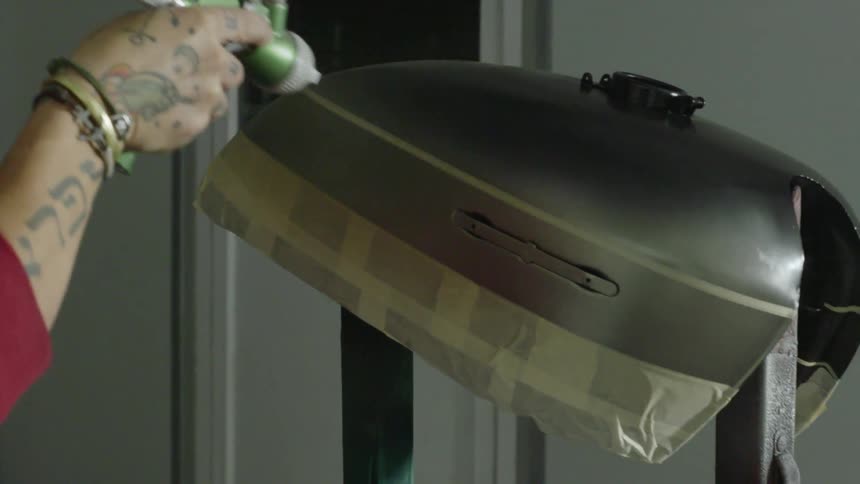 A person is spray painting a metal shell from an engine