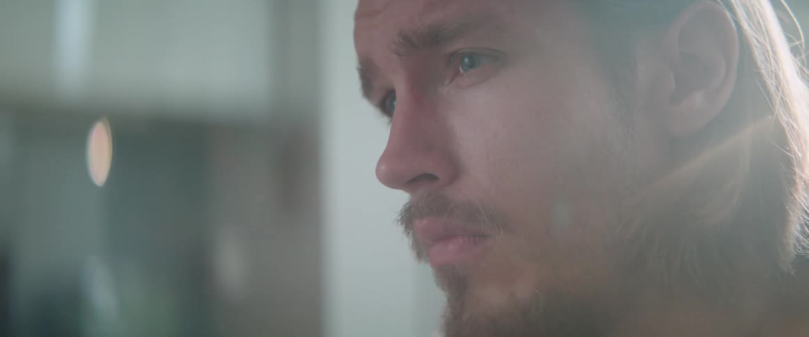 Close up profile shot of a skeptical young man listening in the kitchen.