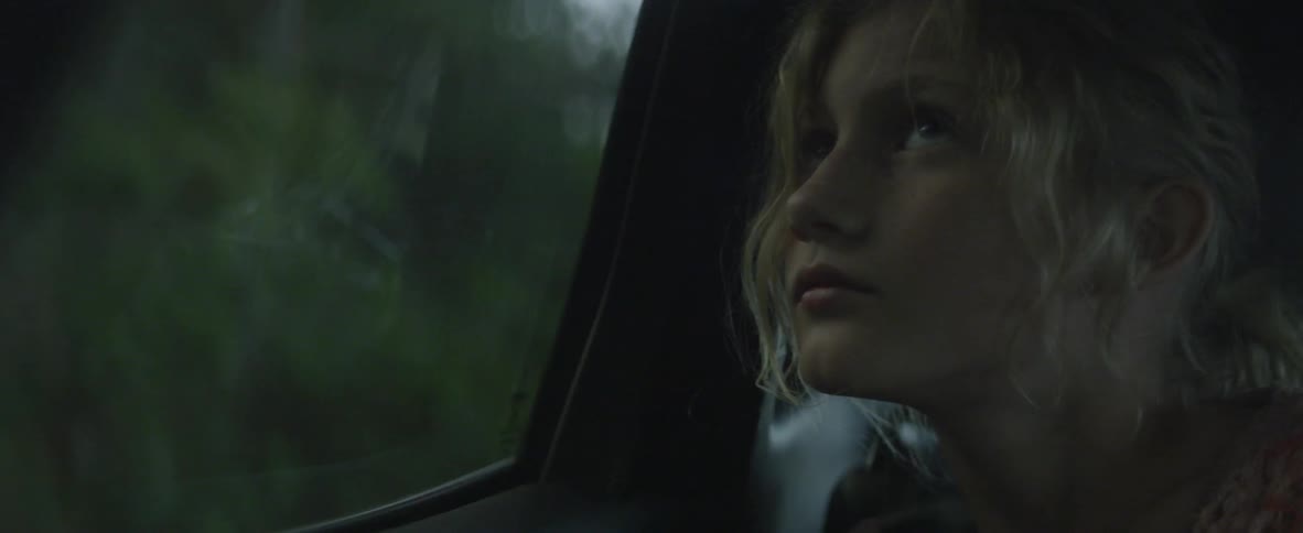 A girl looks out the window of a moving car