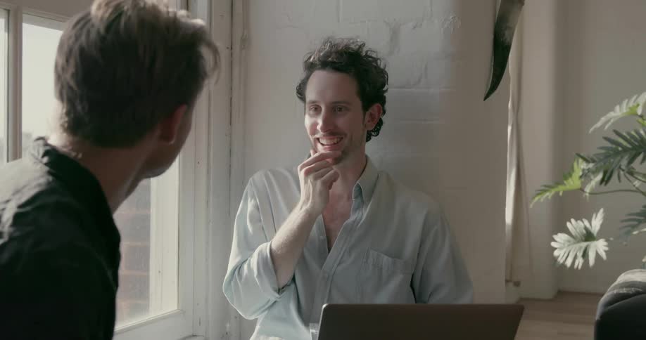 Two men smile and talk