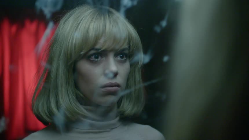 A woman is looking into the mirror, and cries