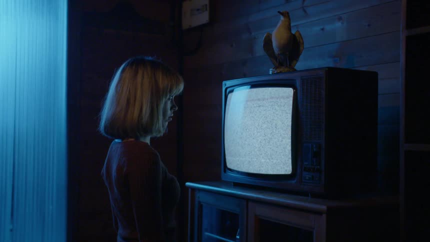 A woman stands close to the television watching
