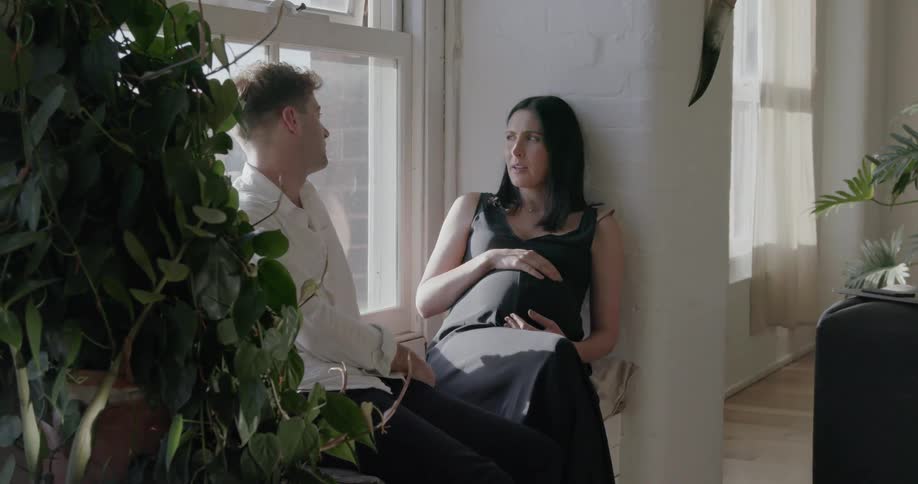 Two people talk together sitting on the window