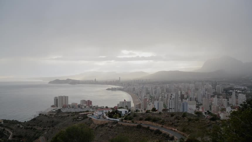 City sits next to a lake under a cloudy sky