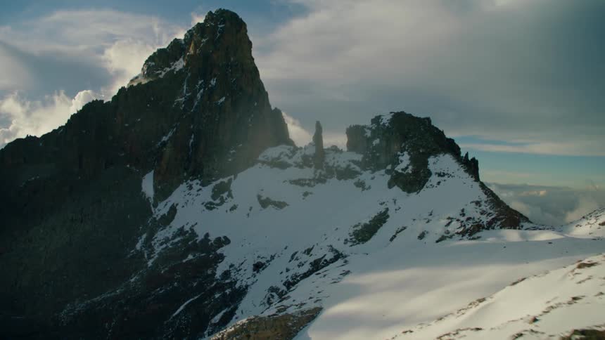 Flying over large mountain with jagged snowy peaks