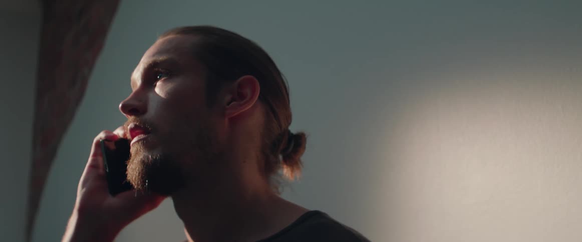 A man looks sad and opens his mouth to speak during a tense call.
