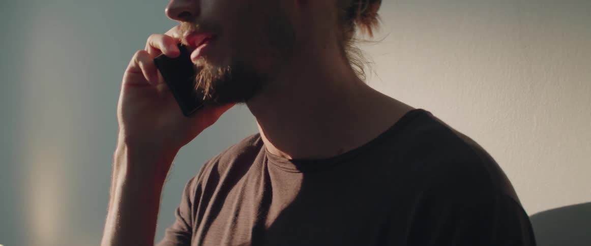 Profile view of a guy having a serious smartphone conversation inside a room.