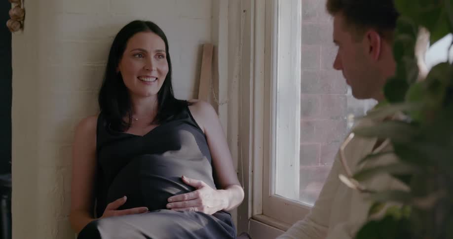 A pregnant woman is sitting and smiling