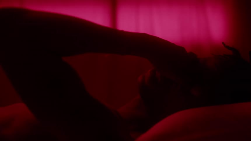 Man lays in bed illuminated by red light