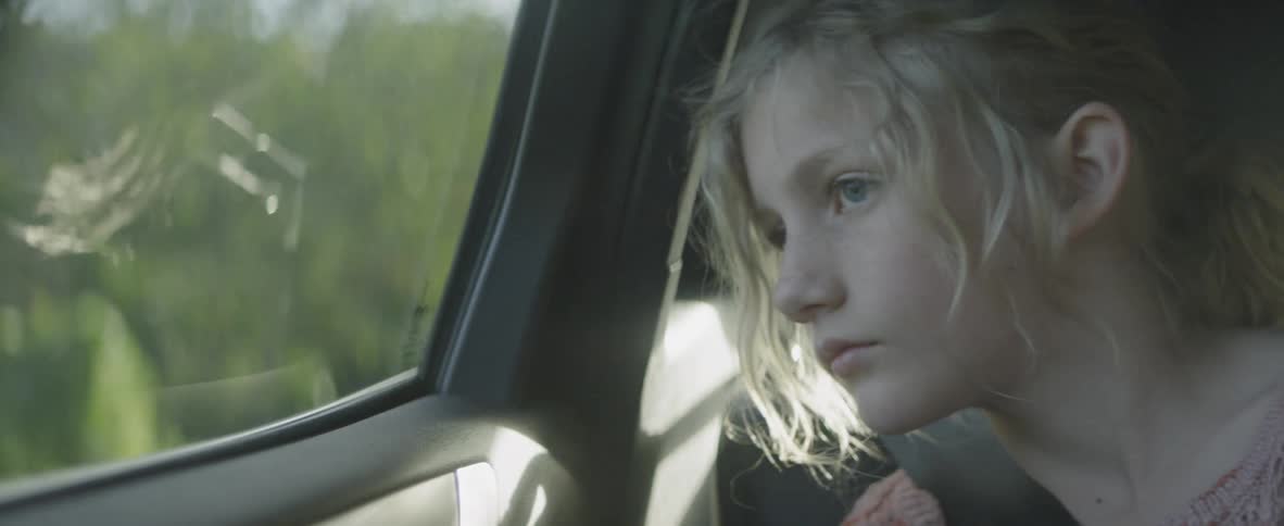 Little girl looking out window as she travels in car