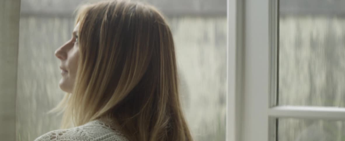 A woman is looking up at the sky as she walks through french doors into a yard