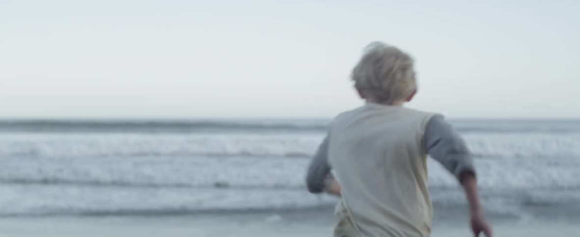 A young boy runs playfully on the beach