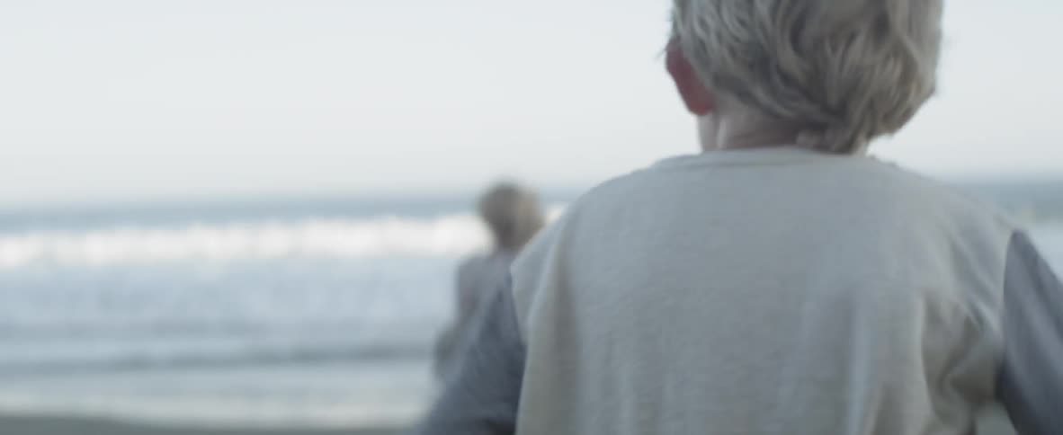 Two children run on the beach