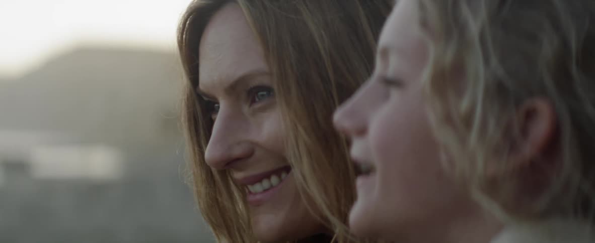 Woman smiles and talks to child outside on a sunny day