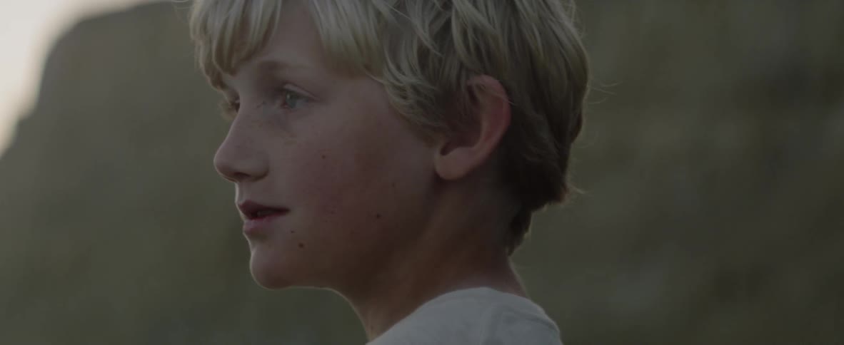 A boy standing outside turns his head