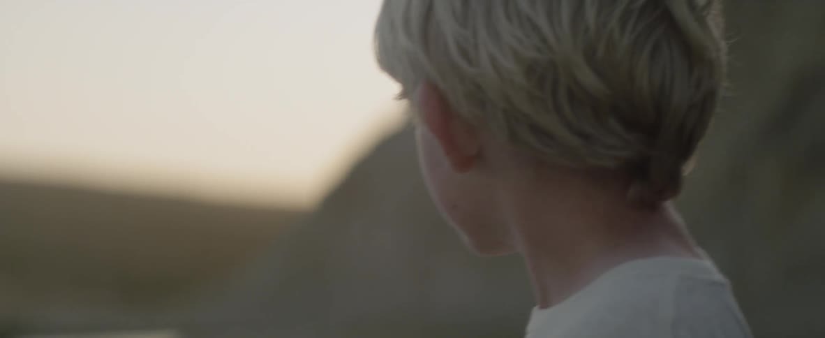Boy stands outside at sunset