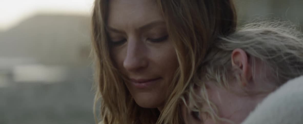 Blond woman rests her head on another person's head