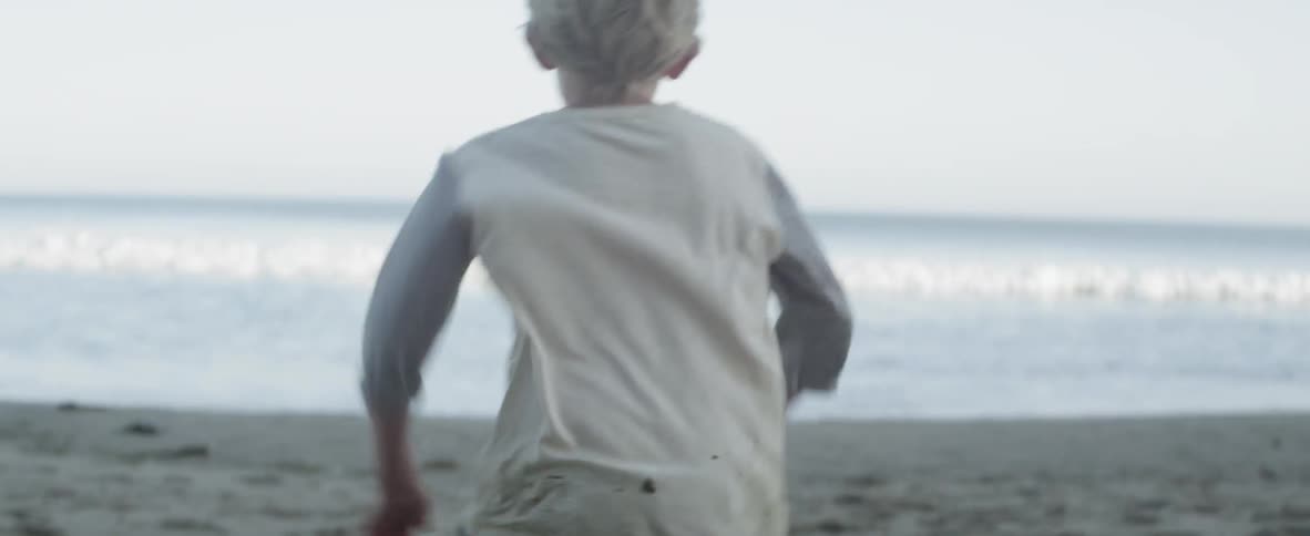 A young boy runs playfully on the beach