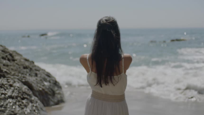 Woman standing at the edge of a beach