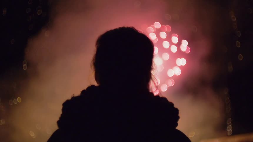 Someone is watching fireworks explode in the night sky