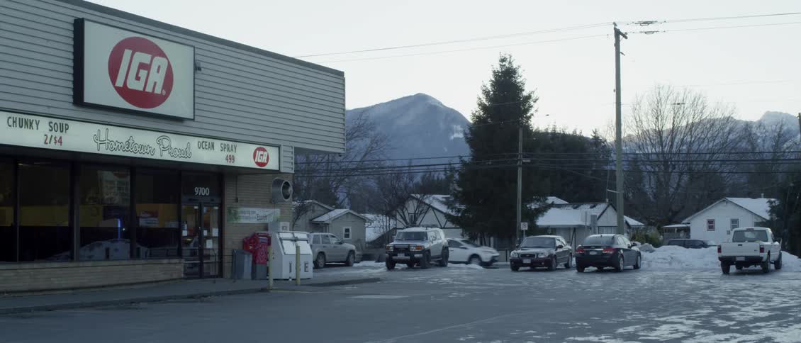 Cars travel past a store and parking lot