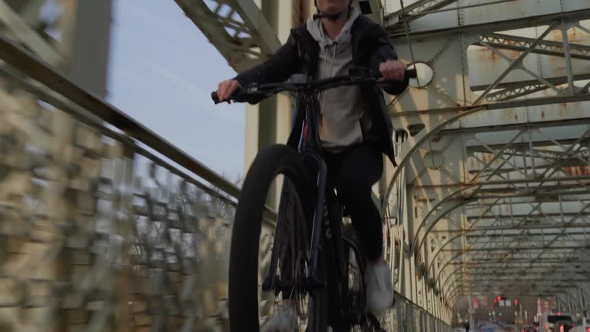 Man rides a bicycle on a bridge under a blue sky