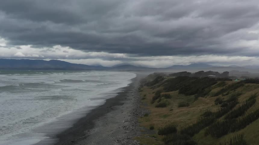 Foamy waves crash into shore under a cloudy sky
