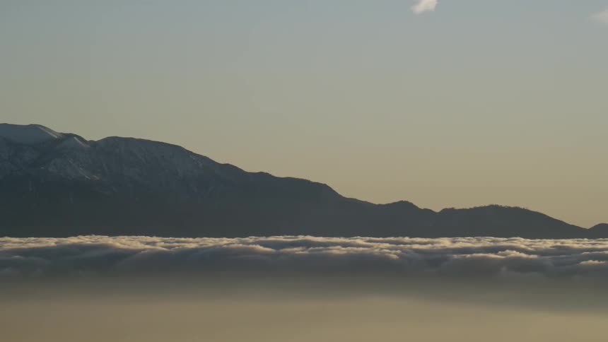 Clouds float near mountains at sunset
