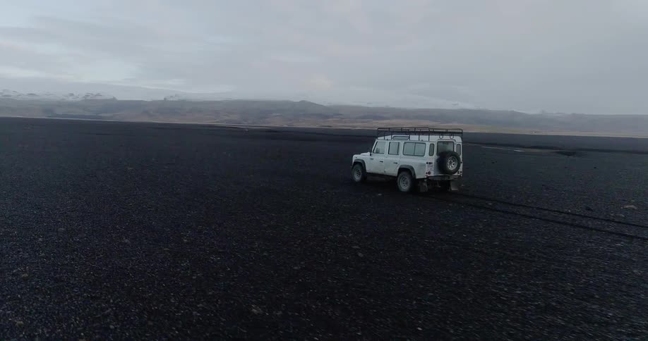 A vehicle drives across a rural dirt field