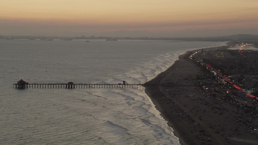 Waves roll into shore under a long pier