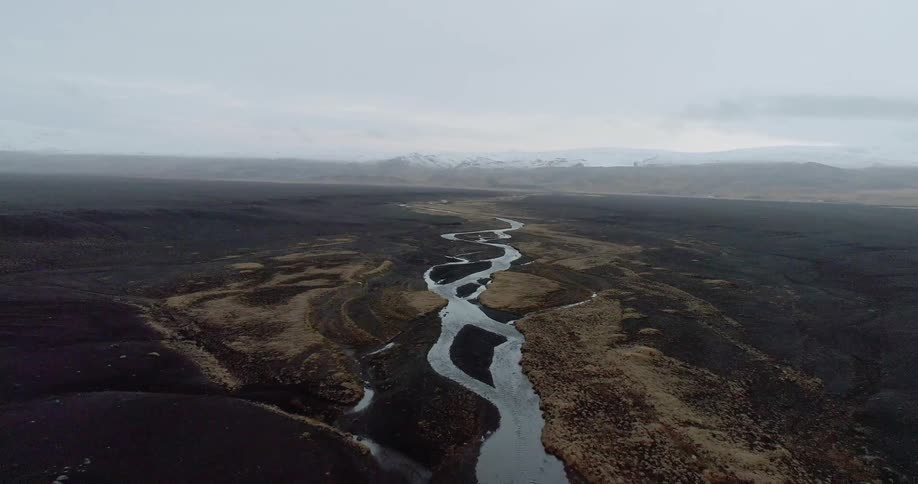 The stream runs through the fields on a cloudy day