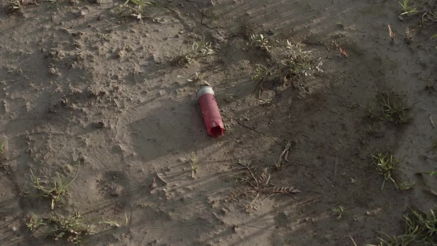 Used shotgun shell lying in a dirt area