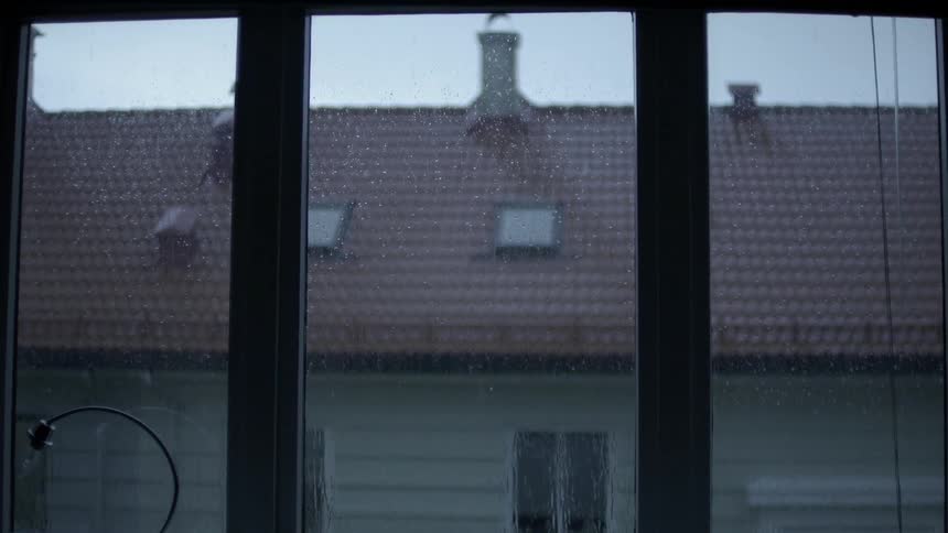 A red shingle room is filmed from a window on a rainy day