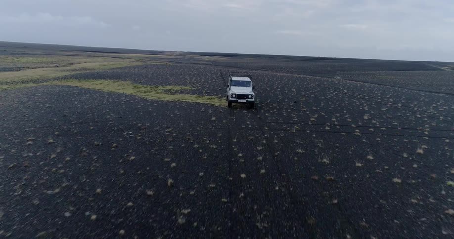 An suv makes tracks in the black sand