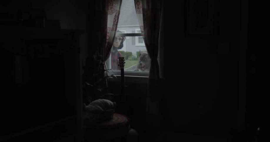 Two people in halloween masks peek inside of the dark home