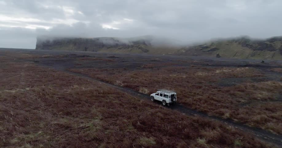 A jeep is driving over some barren landscape