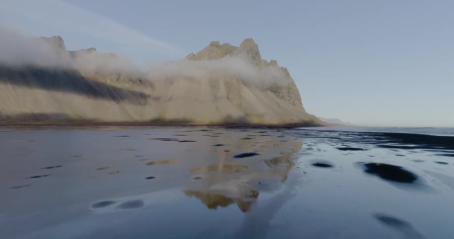 Calm lake sits next to the mountain under a blue sky