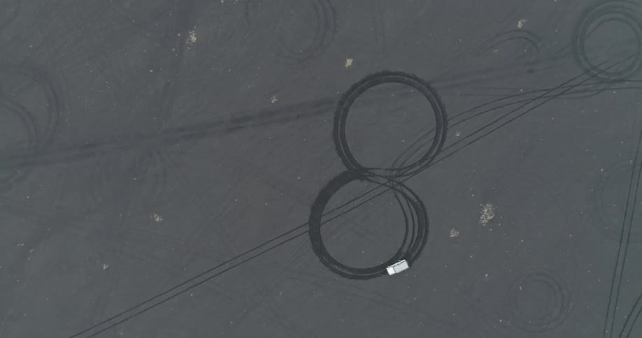 A vehicle drives in a figure 8 in the sand