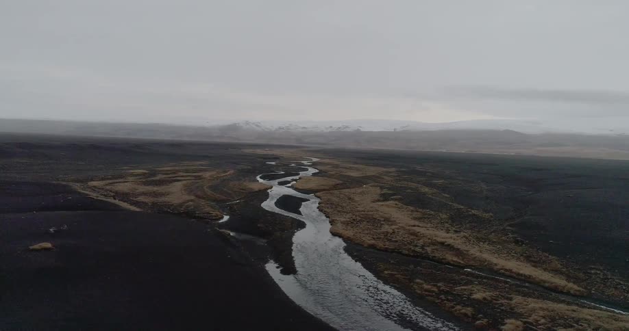 A narrow stream winds through flat land