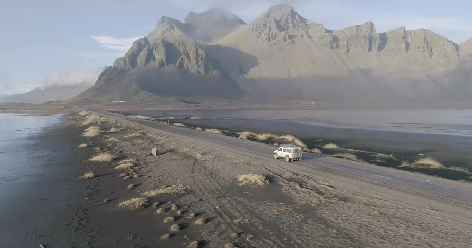 The vehicle drives down the dirt road near the canyons ahead