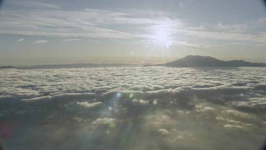 The sun shines on mountains and clouds