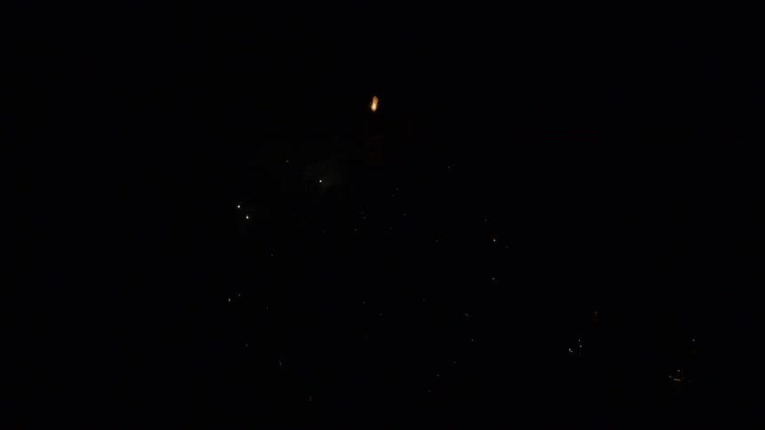 The firework explodes in the night sky above