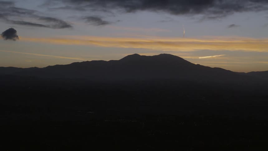 Sun sets over a mountain in shadows