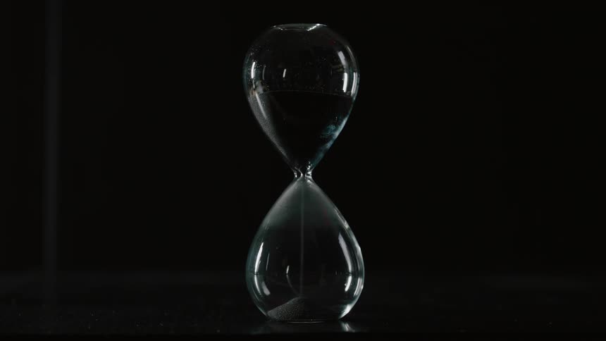 The hourglass sits on a table in the dark running