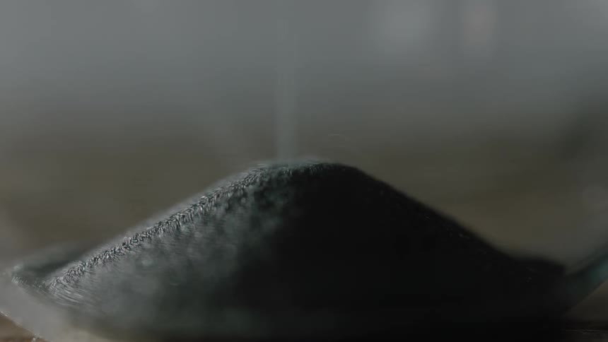 The sand slowly pours into the bottom of the hourglass